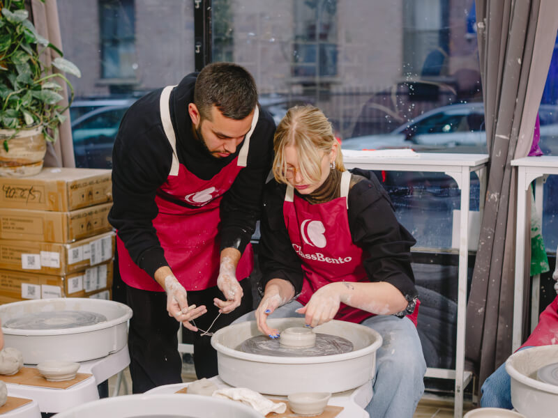 couple taking a wheel throwing pottery class